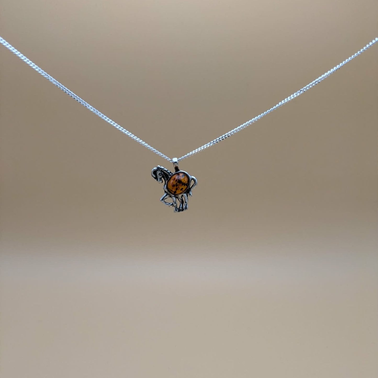Horse pendant in silver with cognac amber