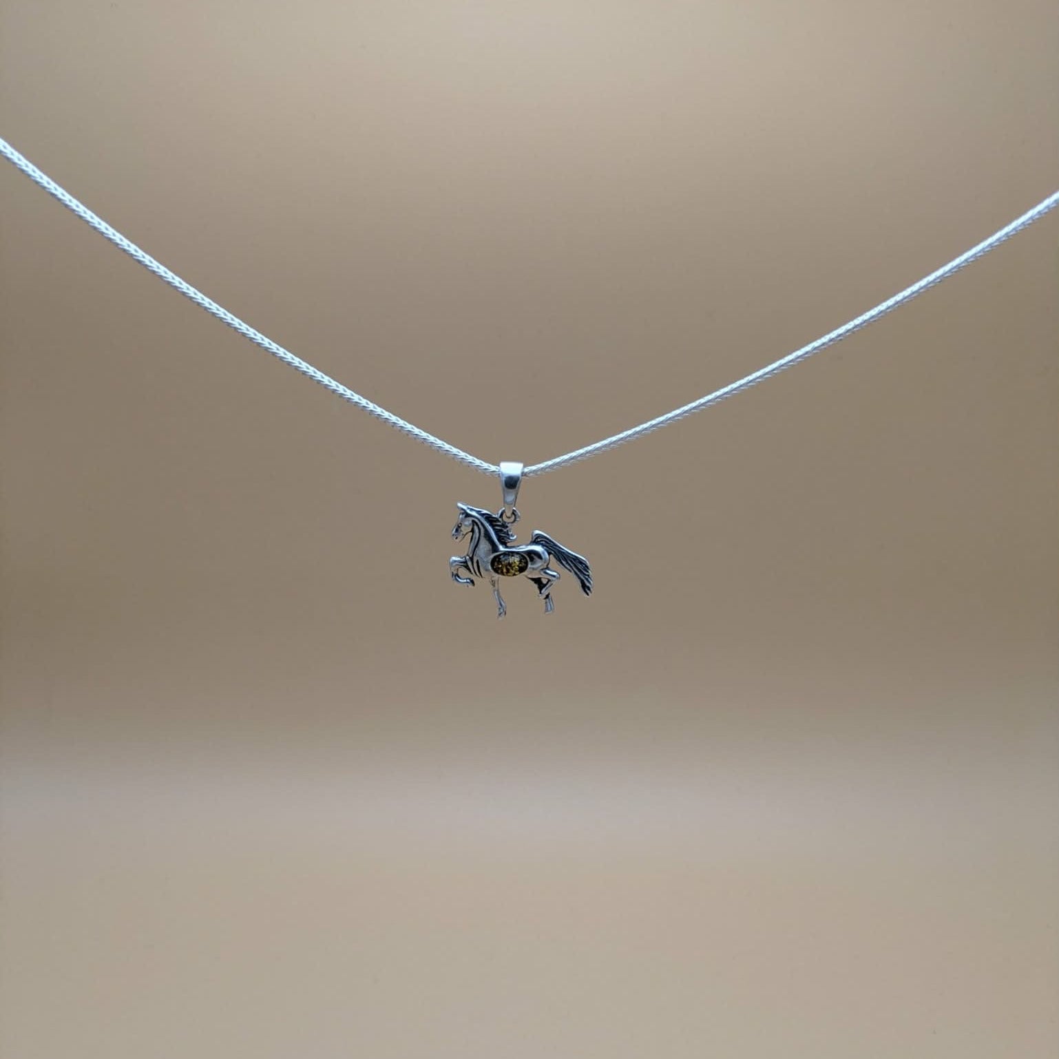 Silver pendant shaped as a  horse with green amber